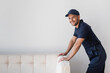 © LIGHTFIELD STUDIOS - happy workman standing near white couch and smiling at camera