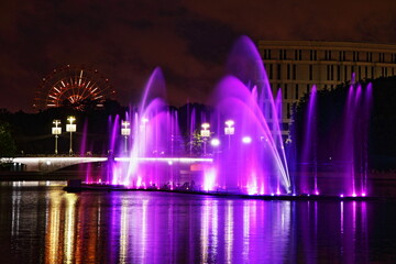 Poster - Colorful purple fountains on Svisloch River on the Ferris wheel background in the Yanka Kupala Park at summer night, a beautiful view of Minsk , a famous national landmark of the capital of Belarus