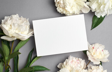 Greeting or invitation card mockup with copy space and white peony flowers on grey