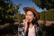 © ADDICTIVE STOCK - Cheerful Asian woman eating ripe apple in garden in countryside