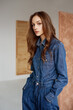 Fashionable woman wearing trendy  blue denim shirt, jeans. Model posing in studio with natural day light