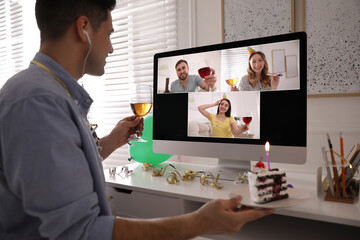 Poster - Man with glass of wine and cake having online party via computer at home during quarantine lockdown