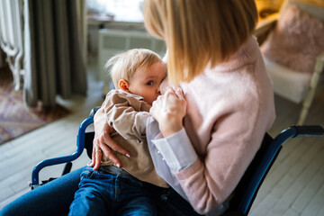young mother with disability in wheelchair breast feeding her child at home