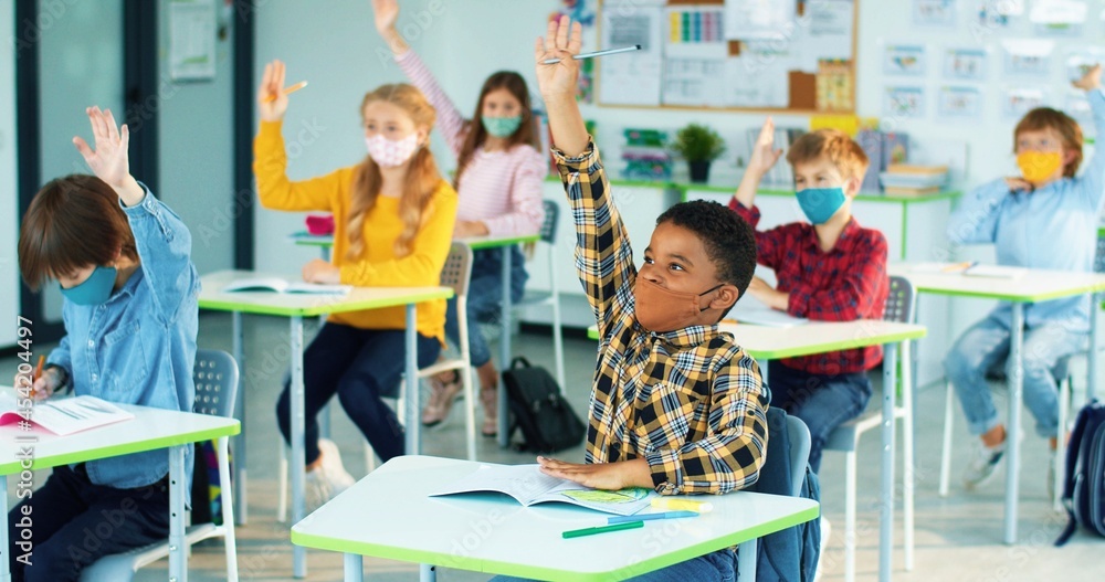 Mixed race Diverse Children Sitting In Classroom Learning And Raising mixed-race-diverse-children-sitting-in-classroom-learning-and-raising