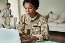 Focused Black Woman Soldier Using Laptop At Table