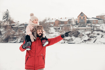 Canvas Print - Handsome bearded young dad and his little cute daughter are having fun outdoor in winter. Enjoying spending time together. Family concept