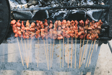 Top view of Sate Kambing or goat satay on red fire grilling by people.