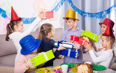 Smiling russian children giving presents to little boy during party