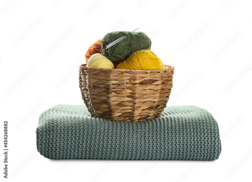 Wicker basket with knitting yarn and plaid on white background