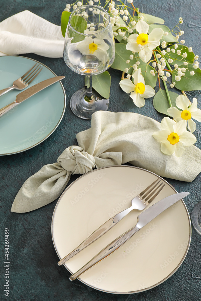 Beautiful table setting with narcissus flowers on dark background