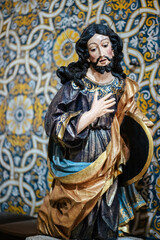 Canvas Print - Wooden sculpture of a saint on a background of azulejo tiles