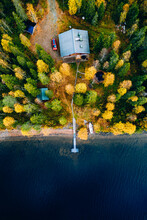 Aerial View Of Yellow And Orange Autumn Forest With  Cottage And Wooden Pier By Blue Lake.