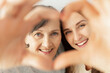 © Vadim Pastuh - Close-up portrait of lovely senior mother and grown daughter look at the camera through heart from palms, heart shaped framing, happy retired mom and adult daughter laughing