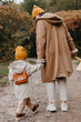 © Ananass - Young happy and smiling mom with her little daughter in arms hugging and kissing spending a weekend on a walk in autumn park. selective focus, noise effect, Autumnal mood