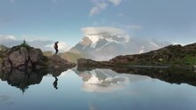 Young Woman Hiking Glacier Lake Top Of Mountain At Sunset. 4K Drone Footage With Snowy Mountains Peaks On Motion Background, North Cascades National Park, Washington USA Nature Boarder With Canada