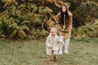 © Ananass - Young happy and smiling mom with her little daughter in arms hugging and kissing spending a weekend on a walk in autumn park. selective focus, noise effect, Autumnal mood