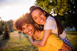 © deagreez - Portrait of attractive adorable affectionate cheerful couple partners having fun piggybacking spending weekend at forest outdoors