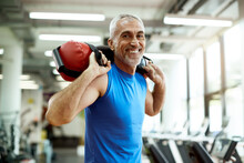 Happy Mature Sportsman Exercises With Sandbag During Sports Training At Gym.