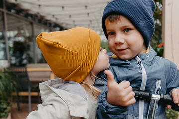 Wall Mural - portrait of little brother and sister who went for a walk together in the autumn city. Together they show a thumb that symbolizes their joy