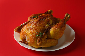 Plate with roast turkey on red background