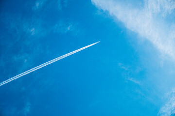 airplane flying in the blue sky among clouds and sunlight