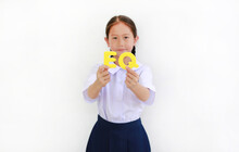 Asian Little Girl Child In School Uniform Holding Alphabet EQ (Emotional Quotient) Text On Her Face Over White Background. Education Concept. Focus At Text In Hands