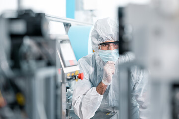 scientists wearing protective clothing inspect mask making machines in a laboratory at an industrial
