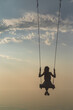 © Oleh Voinilovych - Silhouette of a beautiful young girl who is swinging on a swing against the background of the sky and sea waves. Real photo without graphic editing.