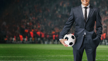 smiling businessman in formal wear with soccer ball in the big stage