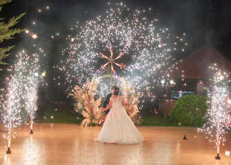 a woman and a bride are standing on the street and looking at a turntable with glowing lights, a wedding fireworks display