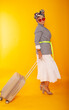 © Marina Chernivetskay - a woman with a suitcase on a yellow background in isolation. Traveler