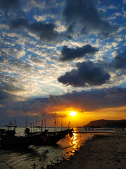 Wall Mural - Wooden boat moored in shallow water near the beach at sunset. Romantic landscape.