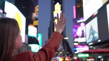 Young Woman Tourist At Times Square At Night Raise Her Hand Up. Manhattan.