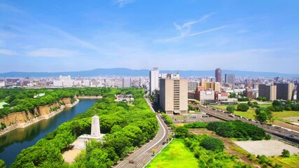 Wall Mural - Osaka, Japan. Aerial view of Castle Park in Osaka, Japan with modern skyscrapers at the background. Cloudy sky during the hot day with car traffic