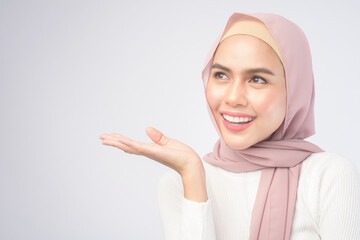 Wall Mural - Portrait of young smiling muslim woman wearing a pink hijab over white background studio.