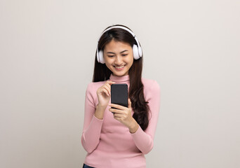 Beautiful young asian women choose song and play music from smartphone connection with wireless headphone having fun in home. Teenage girl listen to the music enjoy relaxing on isolated background.