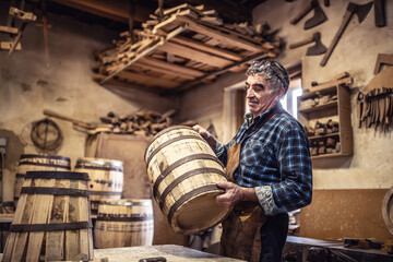 Wall Mural - Craftsman puts finished wooden barrel on a table in his rustic workshop