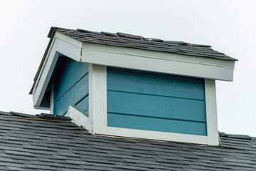 Closeup of a wooden dormer under a white sky