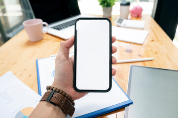 Wall Mural - Cropped shot of man hand holding blank screen smartphone while sitting at office desk.