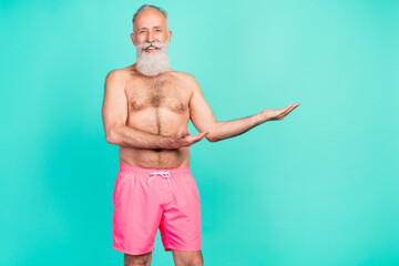 Wall Mural - Photo of reliable cheerful mature man hands presenting empty space wear pink shorts isolated turquoise color background