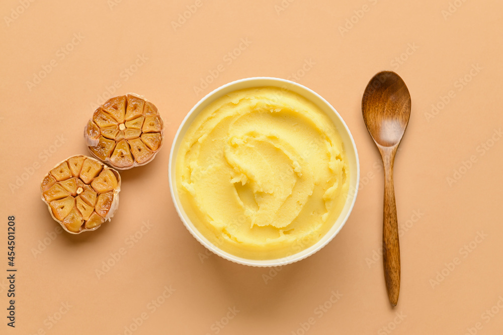 Bowl of tasty mashed potatoes with garlic on color background