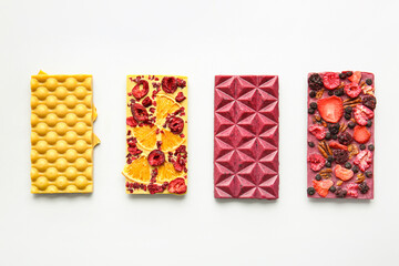 Handmade chocolate bars with fruits, berries and nuts on white background