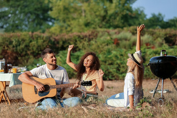 Poster - Young man playing guitar at barbecue party on summer day