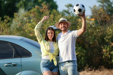 Poster - Young couple with ball at barbecue party on summer day