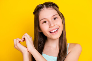 Sticker - Close-up portrait of attractive cheerful girl showing heart shape isolated over bright yellow color background