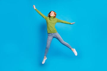 Wall Mural - Full length photo of carefree cheerful lady raise hand fist look empty space flying isolated on blue color background