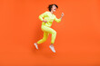 © deagreez - Full length body size view of attractive cheerful girl jumping running action isolated over bright orange color background