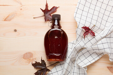 Wall Mural - Beautiful Canadian maple syrup in a bottle on a light wooden background. Pancakes with syrup or honey.
