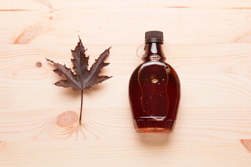 Wall Mural - Beautiful Canadian maple syrup in a bottle on a light wooden background. Pancakes with syrup or honey.
