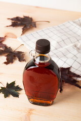 Wall Mural - Beautiful Canadian maple syrup in a bottle on a light wooden background. Pancakes with syrup or honey.
